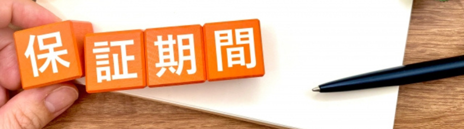 オレンジ色の木製ブロックに「保証期間」と書かれた画像、横にペンとノート