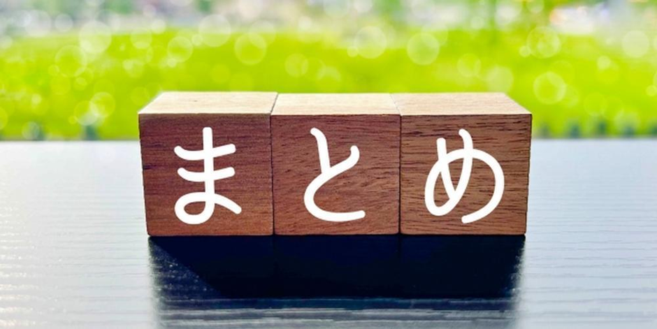 「まとめ」の文字が書かれた木製ブロックと、屋外の緑が広がる背景のイメージ