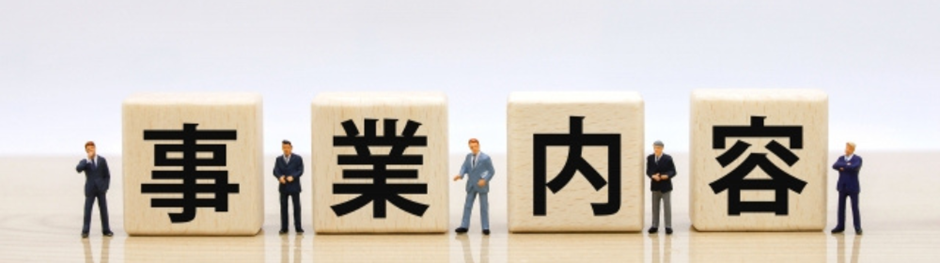 木製ブロックに「事業内容」と書かれ、ビジネスマンのフィギュアが並ぶイメージ