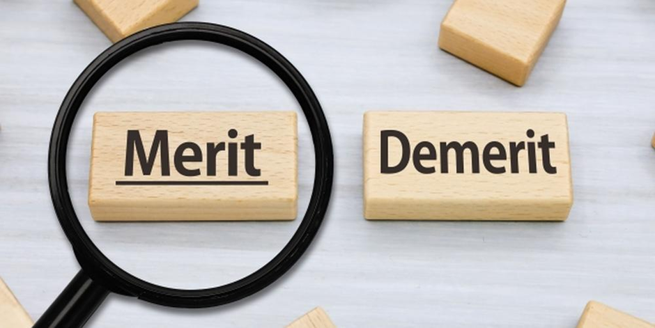 「Merit」の文字が拡大鏡で強調された木製ブロックの画像